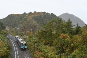 湯の島を背景にひた走る上り列車。トンネル前でひと際大きな警笛を鳴らします。